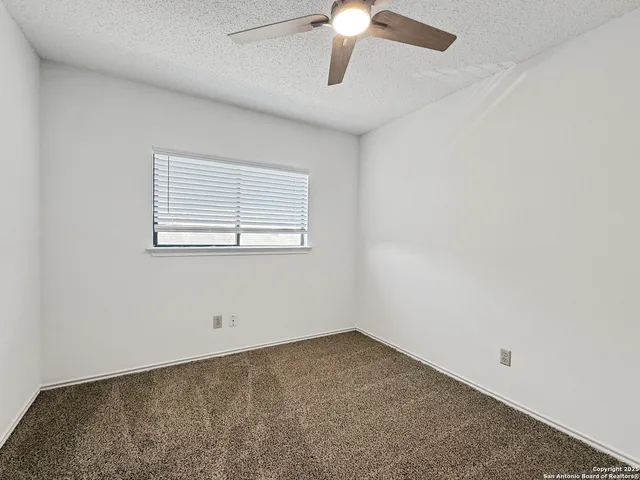 an empty room with a window and a fan