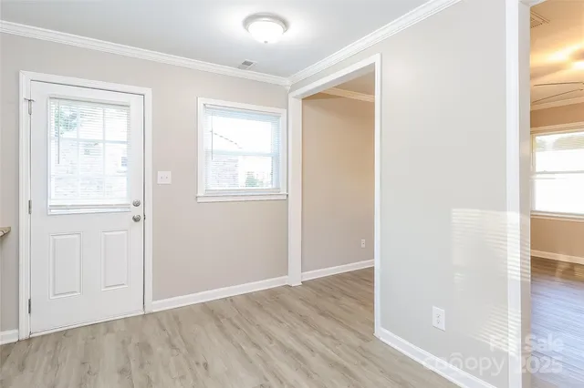 an empty room with wooden floor closet and windows
