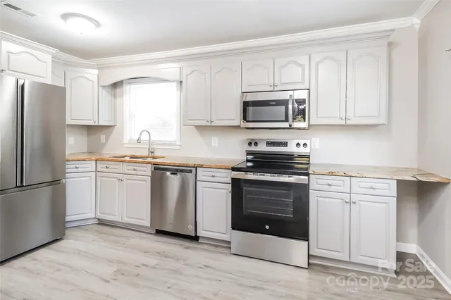 a kitchen with cabinets stainless steel appliances and a window