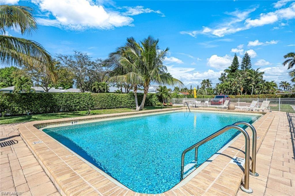 2000 Alamanda Drive, Unit 206 Naples, FL 34102 - Photo 23 of 31 a view of a swimming pool with a yard and palm trees