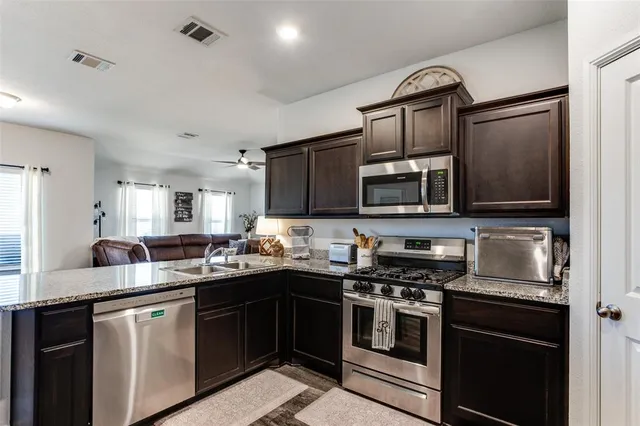 a kitchen with stainless steel appliances granite countertop a refrigerator and a stove top oven