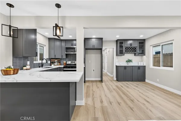 a kitchen with stainless steel appliances kitchen island granite countertop a refrigerator a sink dishwasher a oven with white cabinets and wooden floor