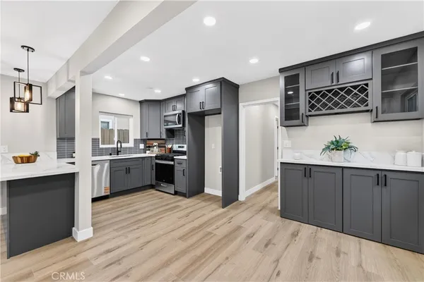 a kitchen with stainless steel appliances kitchen island granite countertop a refrigerator a sink dishwasher and a stove with wooden floor