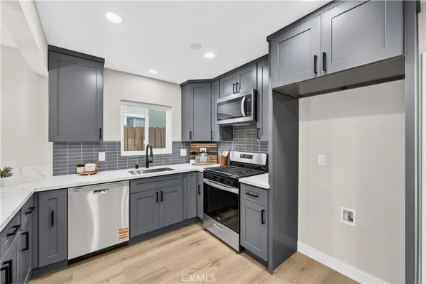 a kitchen with a sink cabinets stainless steel appliances and a window