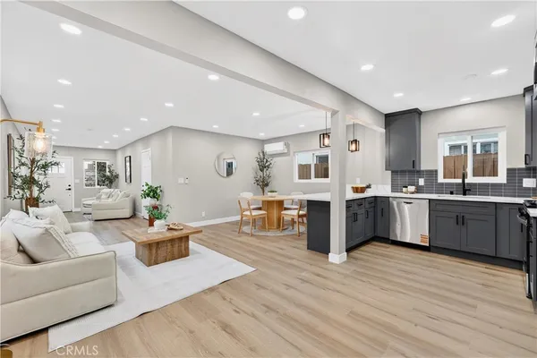 a living room with furniture kitchen view and a wooden floor