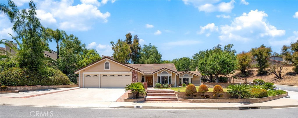 a front view of a house with a garden and trees