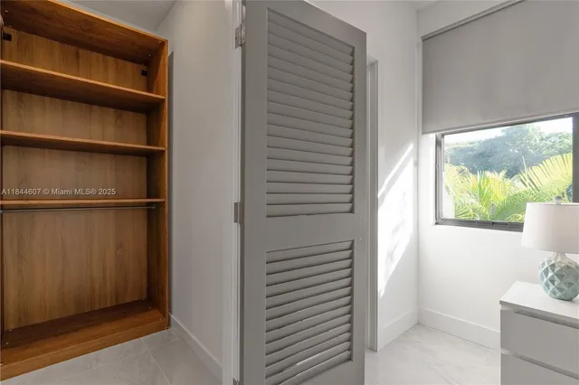a view of an empty room with a window and a bathroom