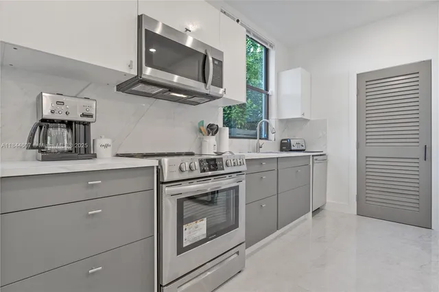 a kitchen with stainless steel appliances granite countertop a stove a sink and a microwave