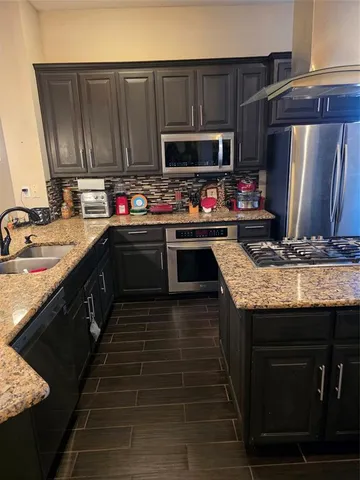 a kitchen with granite countertop a sink wooden cabinets and stainless steel appliances