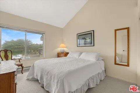 a bedroom with a bed and a lamp on dresser