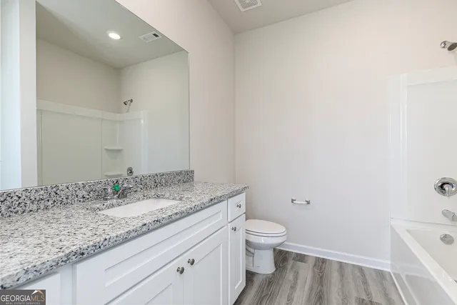 a bathroom with a granite countertop sink a toilet and a bathtub