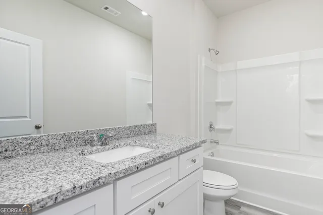 a bathroom with a granite countertop sink a toilet and bathtub