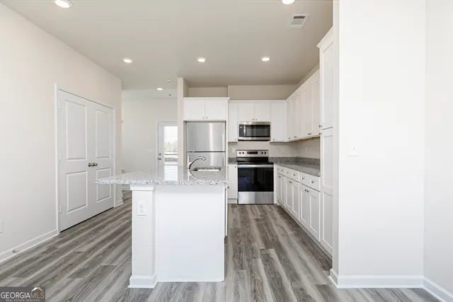 a large kitchen with kitchen island a sink dishwasher stove and white cabinets