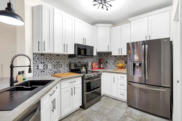 a kitchen with stainless steel appliances white cabinets a sink and a stove