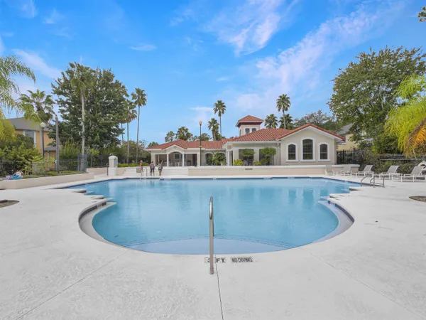 a view of a swimming pool with a yard and palm trees