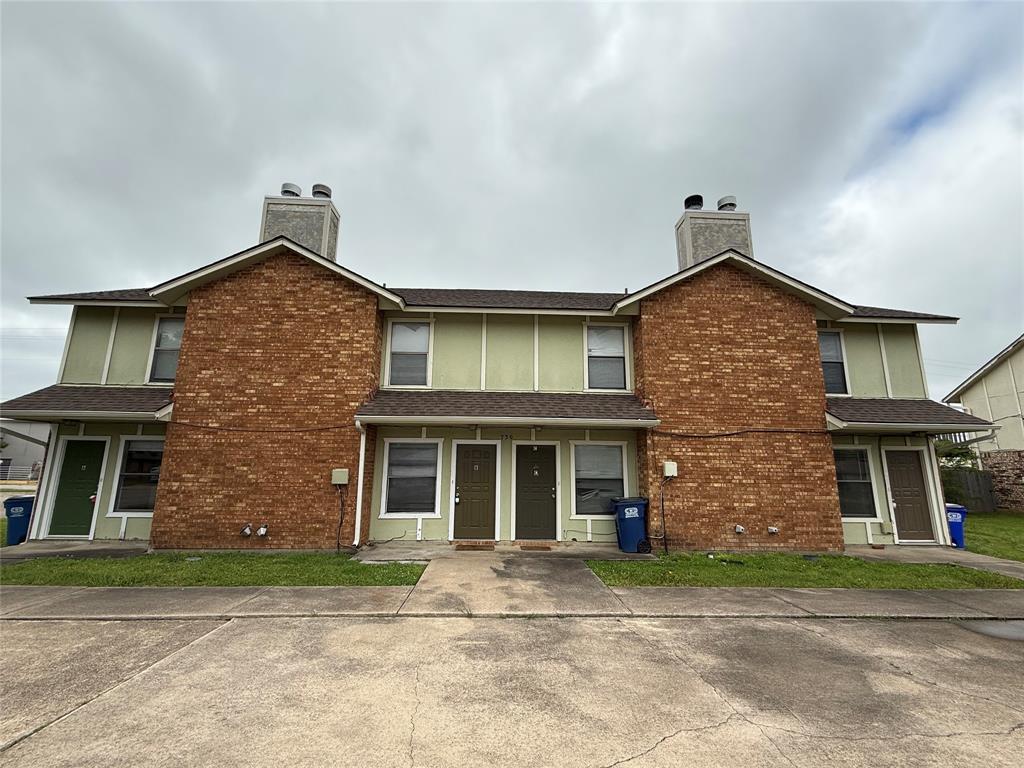Multi unit property with a chimney, brick siding, and a shingled roof