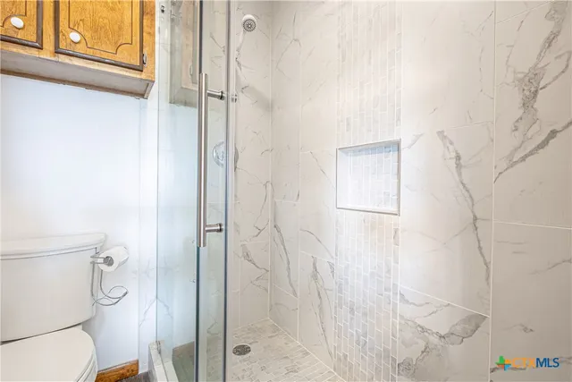 a bathroom with a granite countertop shower and a toilet