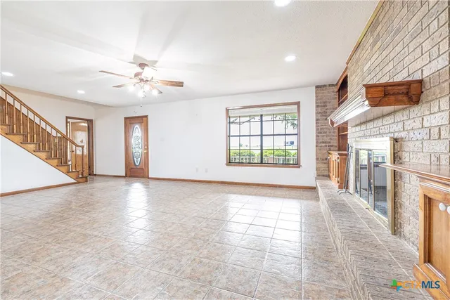 a view of an empty room with window and chandelier fan