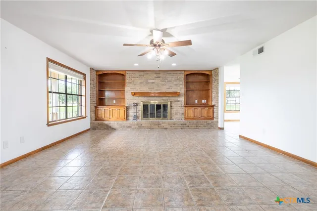 an empty room with fireplace and windows