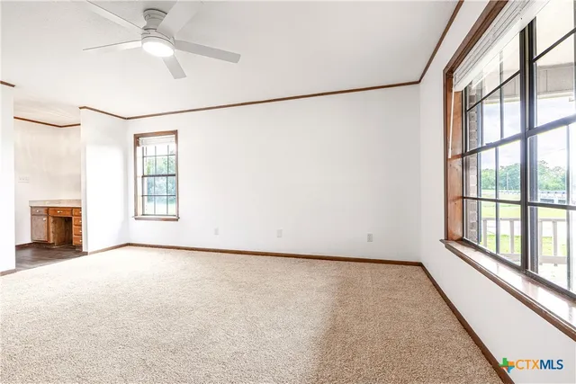 a view of an empty room with a window and a ceiling fan