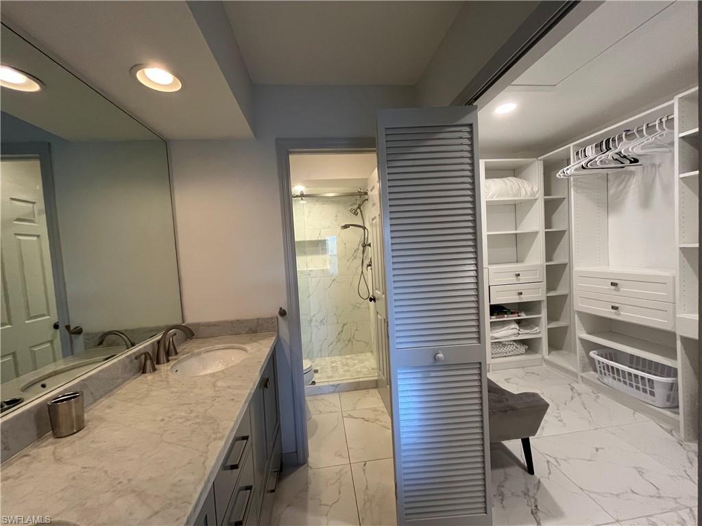 513 Lake Louise Circle, Unit 202 Naples, FL 34110 - Photo 12 of 29 a bathroom with a granite countertop sink a toilet and shower