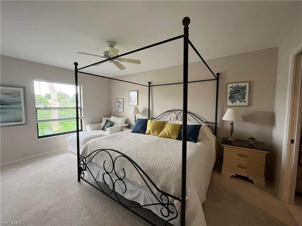 513 Lake Louise Circle, Unit 202 Naples, FL 34110 - Photo 8 of 15 a bedroom with a bed a chandelier and a window