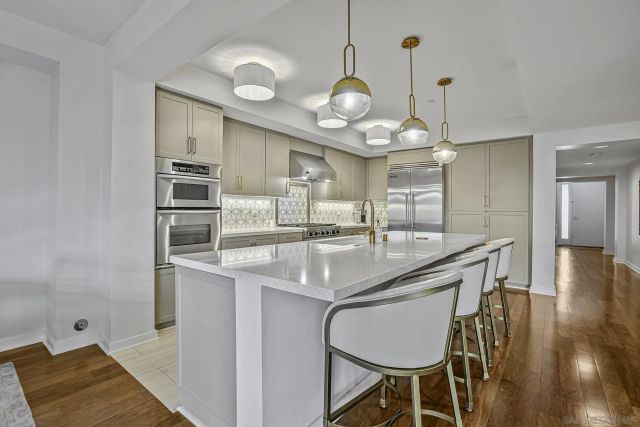 a kitchen with kitchen island stainless steel appliances a chandelier and wooden floor