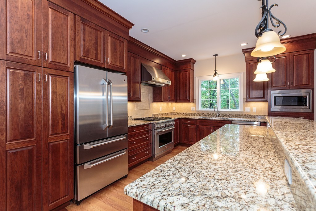 18 Shade Street Lexington, MA 02421 - Photo 12 of 23 a kitchen with stainless steel appliances granite countertop a refrigerator a stove and a sink with wooden cabinets