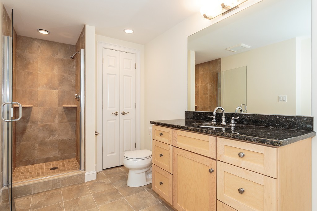 18 Shade Street Lexington, MA 02421 - Photo 19 of 23 a bathroom with a granite countertop sink a toilet a mirror and shower
