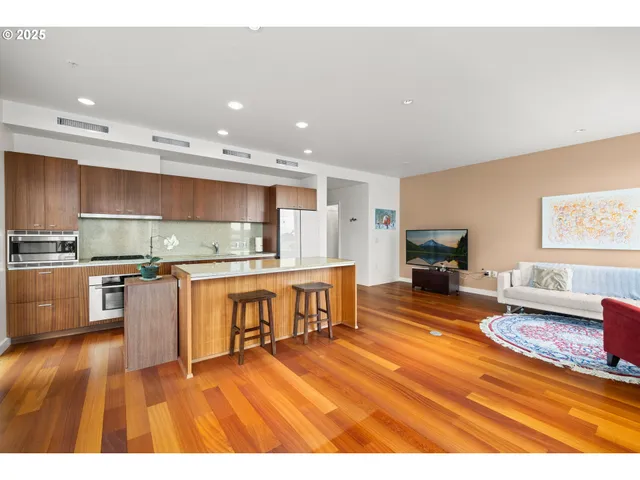 a kitchen with stainless steel appliances granite countertop a refrigerator a stove top oven a sink dishwasher and dining table with wooden floor