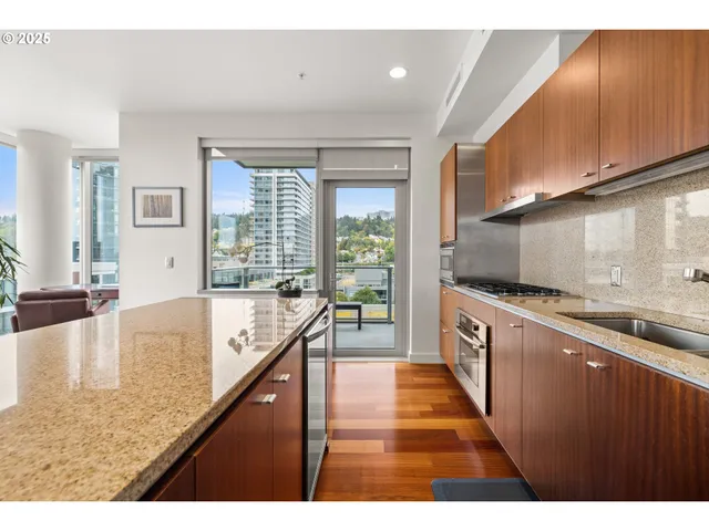 a large kitchen with kitchen island a large counter top and stainless steel appliances