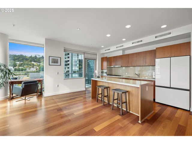 a kitchen with stainless steel appliances granite countertop a stove top oven a sink and a dining table with wooden floor