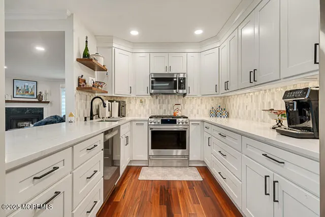 a kitchen with granite countertop white cabinets and stainless steel appliances