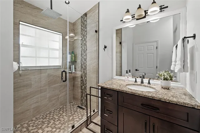 a bathroom with a granite countertop sink a mirror and shower