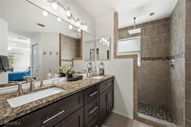 a bathroom with a granite countertop sink a mirror and shower