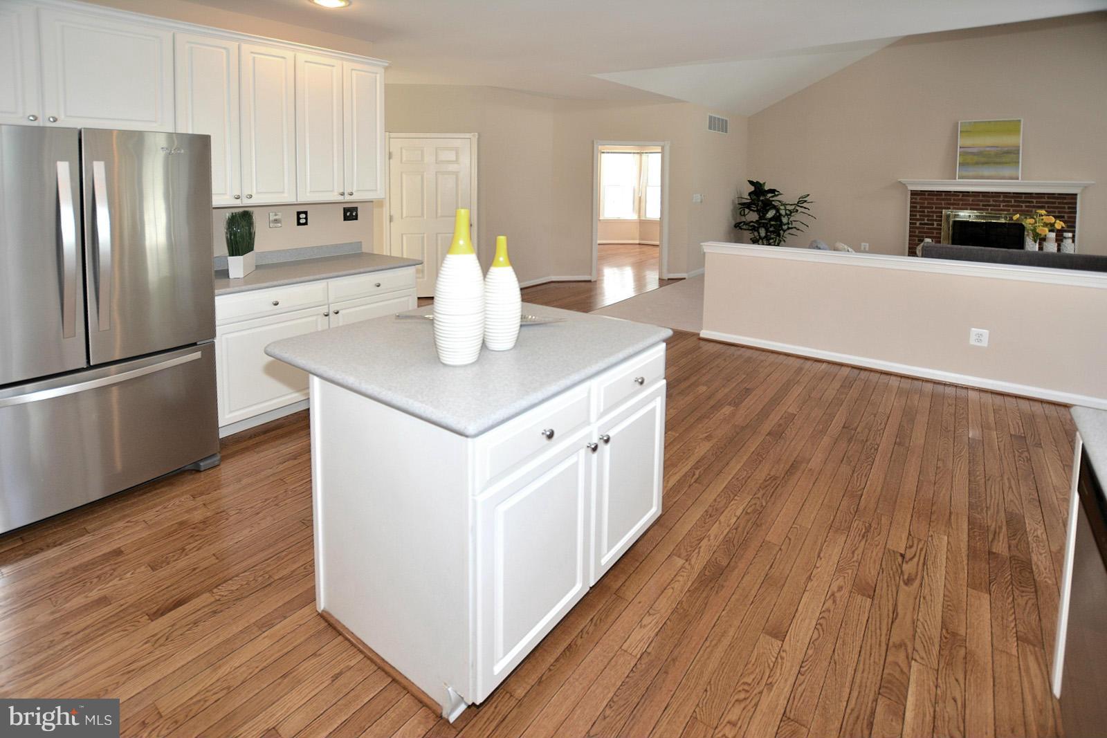 10838 Welbury Court Reston, VA 20194 - Photo 13 of 30 a kitchen with wooden floor white cabinets and stainless steel appliances