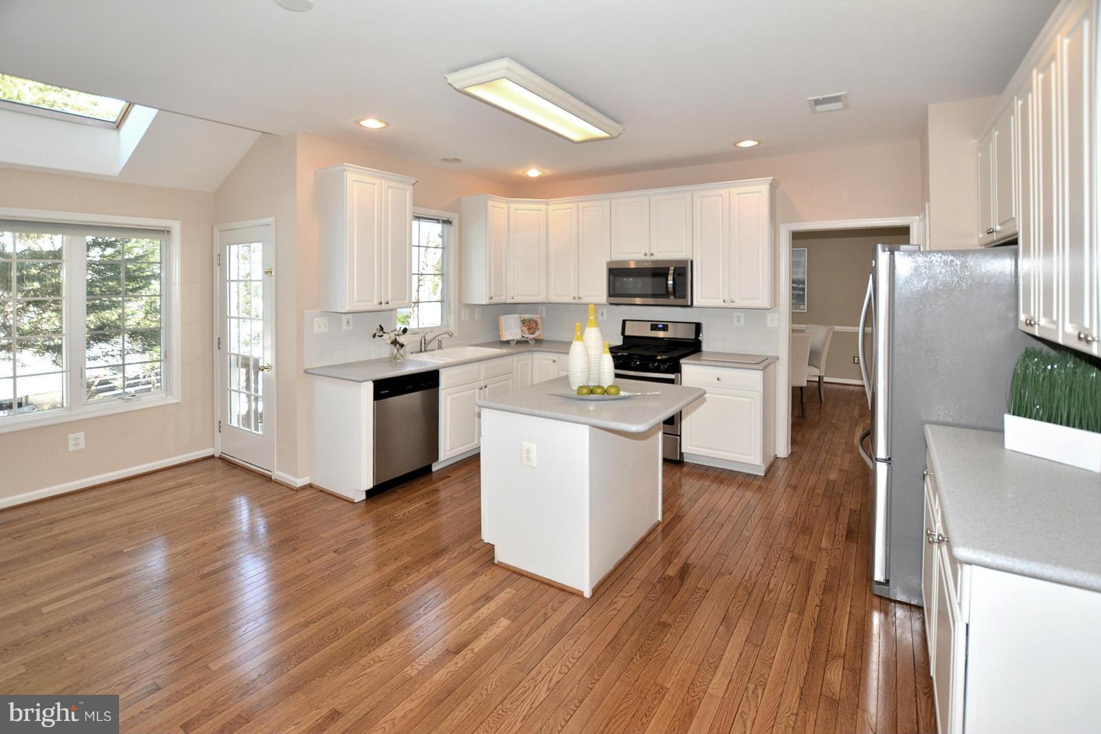 10838 Welbury Court Reston, VA 20194 - Photo 9 of 30 a kitchen with stainless steel appliances a microwave a stove a sink dishwasher a refrigerator and white cabinets with wooden floor
