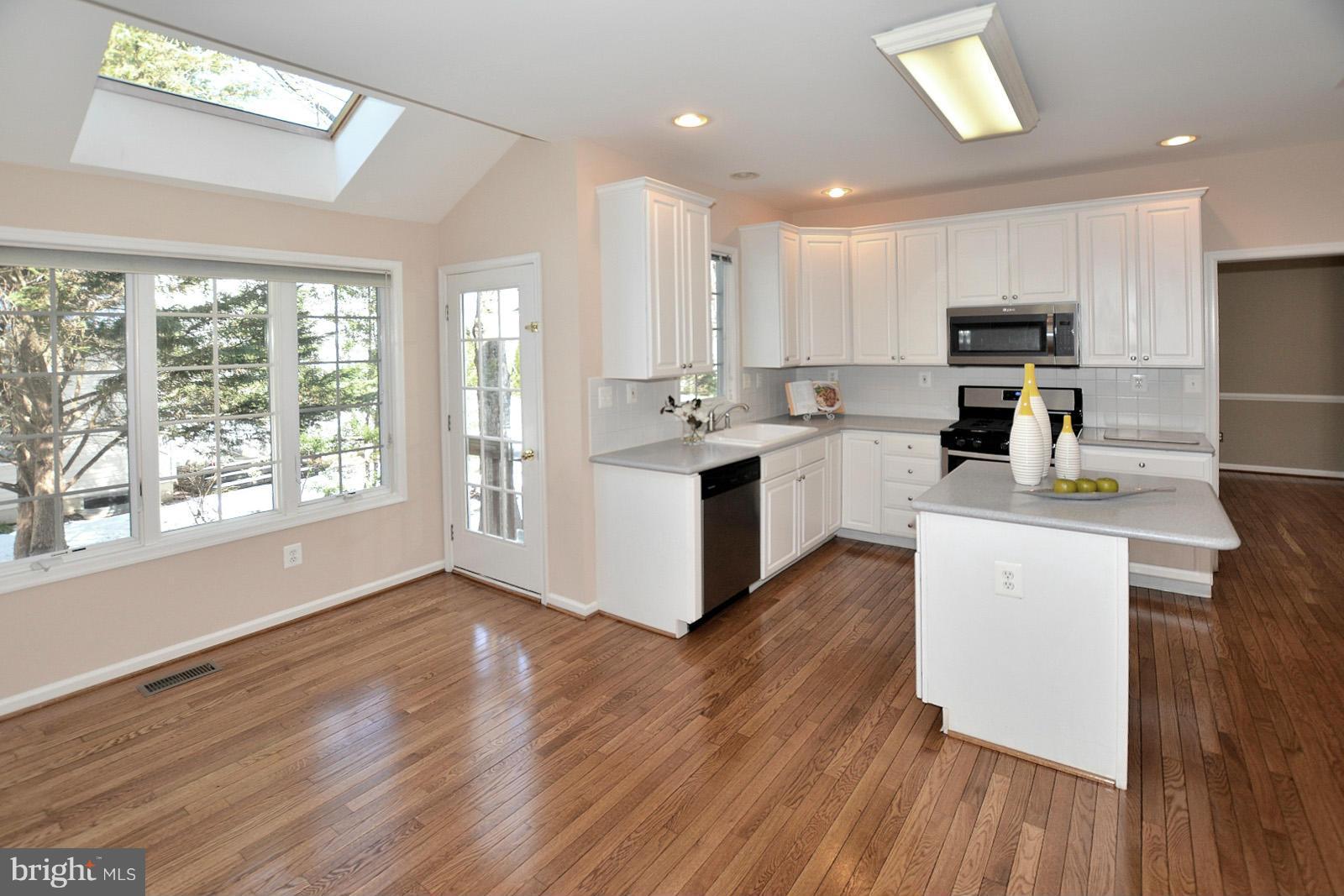 10838 Welbury Court Reston, VA 20194 - Photo 10 of 30 a kitchen with stainless steel appliances granite countertop a stove top oven a sink dishwasher and a refrigerator with wooden floor