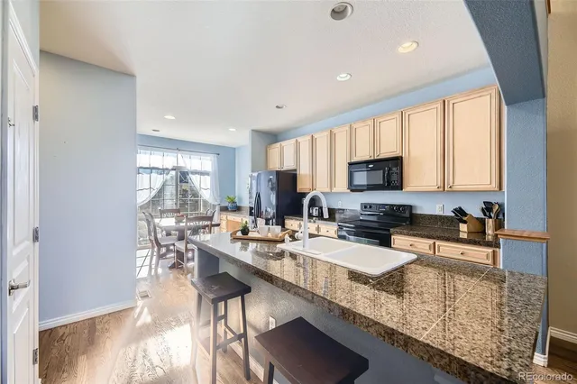a large kitchen with granite countertop lots of counter top space a sink a window and stainless steel appliances