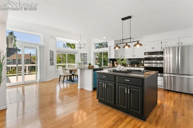 a kitchen with stainless steel appliances granite countertop a table chairs and a wooden floors