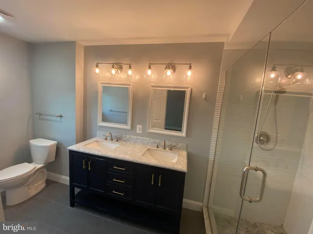 a spacious bathroom with a double vanity sink toilet and a mirror