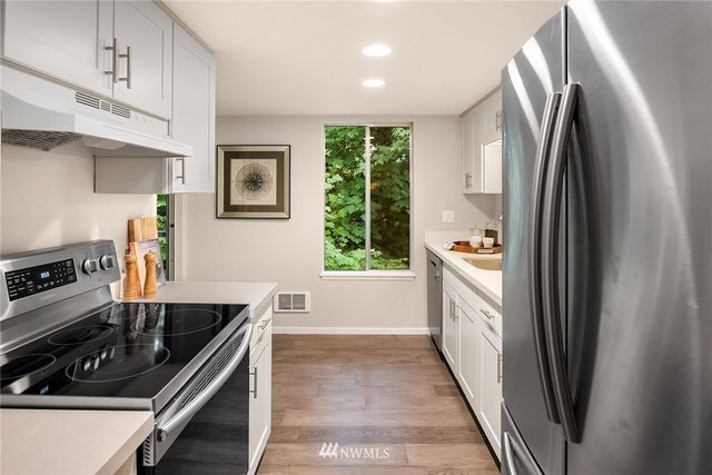 a kitchen with stainless steel appliances a sink a stove a refrigerator a sink a counter space and cabinets