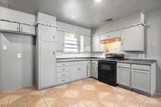 a kitchen with granite countertop a sink cabinets stainless steel appliances and a window