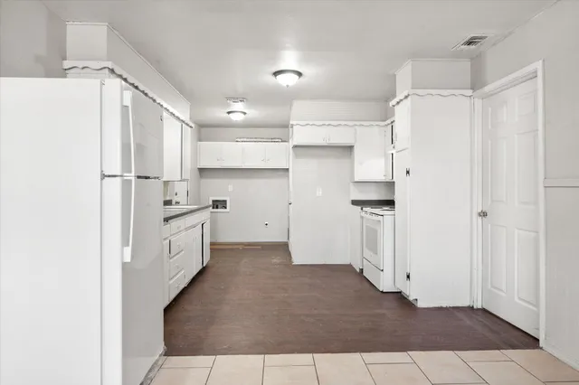 a kitchen with kitchen island granite countertop white cabinets and white appliances