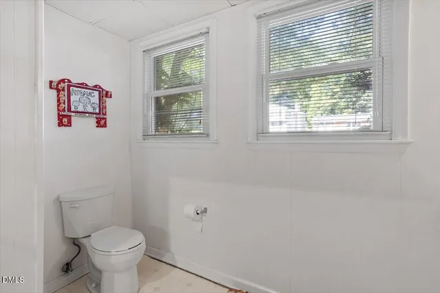 a white toilet sitting next to a window in a bathroom