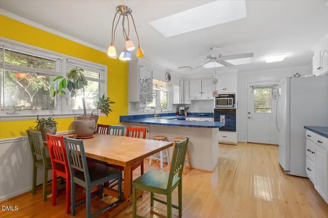 a dining room with stainless steel appliances kitchen island granite countertop a table chairs and a refrigerator