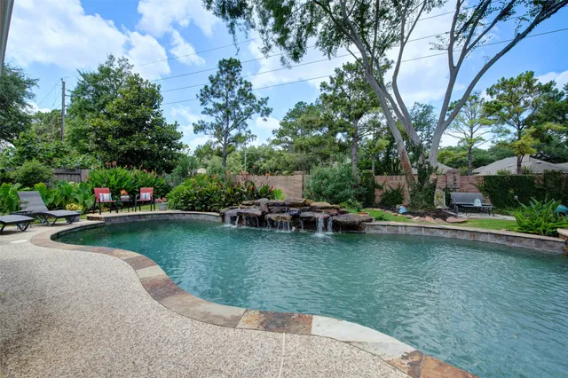 a view of swimming pool with outdoor seating and trees in the background