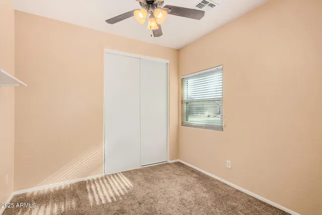 an empty room with a window and a ceiling fan