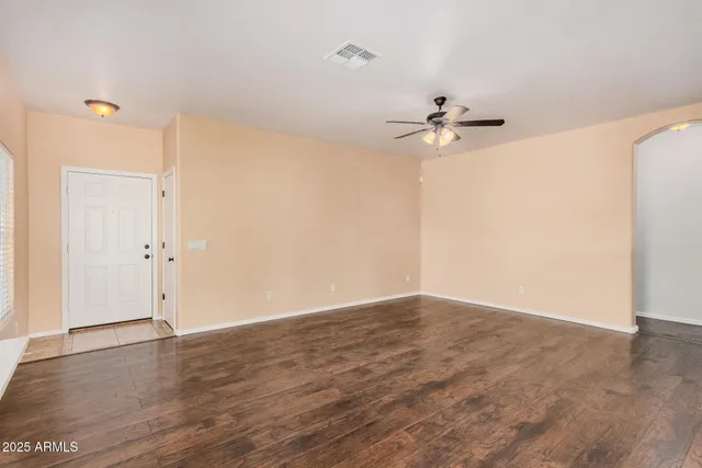 an empty room with wooden floor and a kitchen