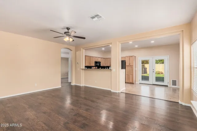 a view of an empty room with kitchen and window